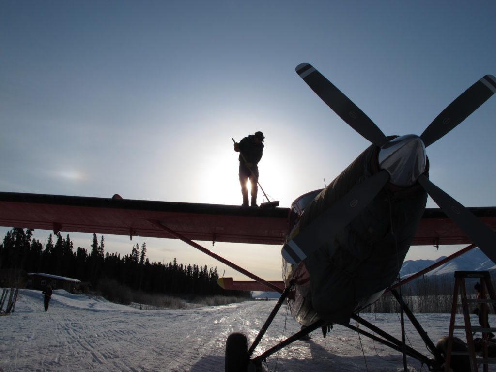 Paul Claus sweeps frost off the wing of the Turbine Otter at the Ultima Thule Lodge airstrip.
