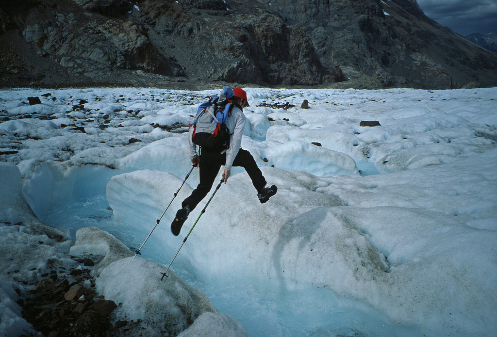 – Ben Ditto leaping across a gushing glacier river in the Rio Electico valley of Patagonia.